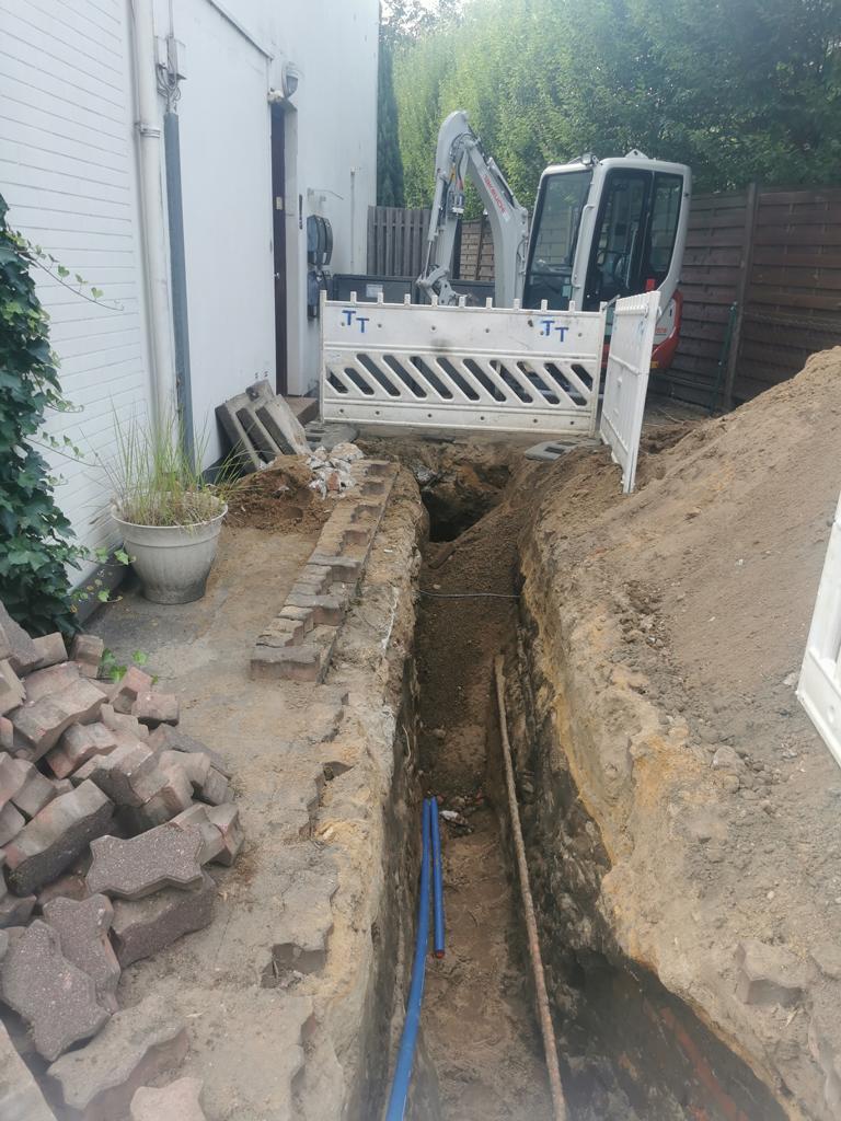 Graben für eine Wasserleitung. Im Hintergrund eine Absperrbarke